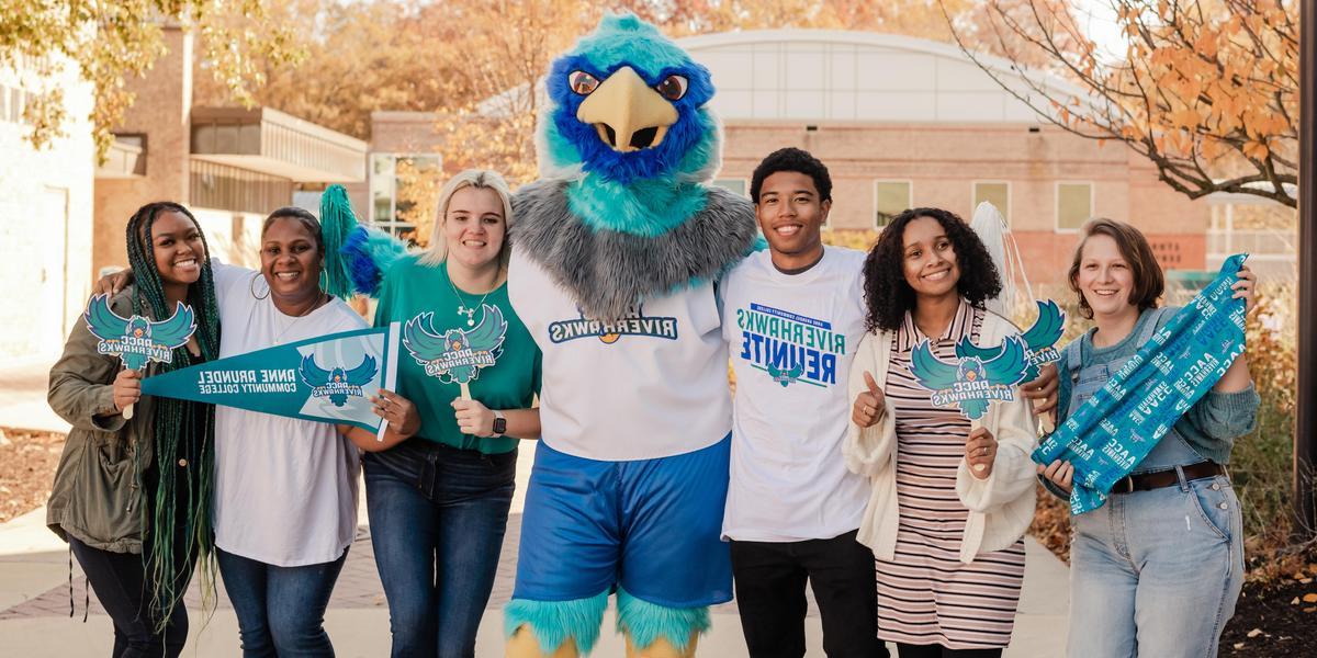 A group of students posing with AACC mascot, Swoop, while holding AACC gear.